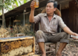 Mật ong dú có kết tinh không và xử lý thế nào? 19 Người nuôi ong tại farm Đồng Nai soi hũ mật ong dú dưới ánh sáng tự nhiên